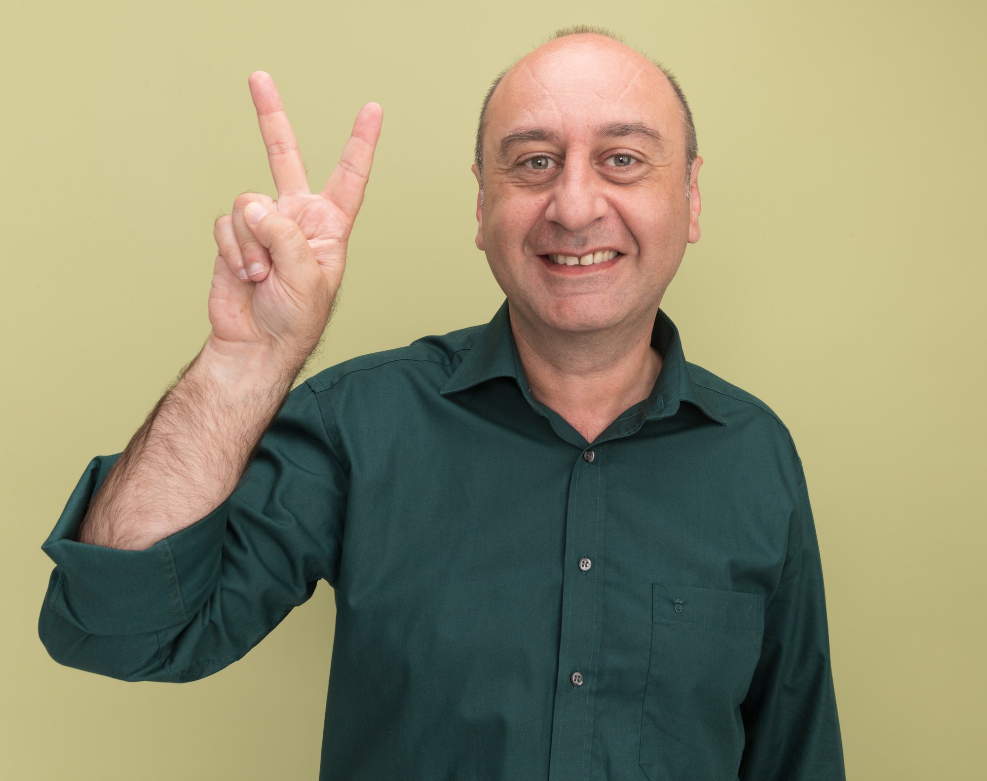 smiling-middle-aged-man-wearing-green-t-shirt-showing-peace-gesture-isolated-olive-green-wall